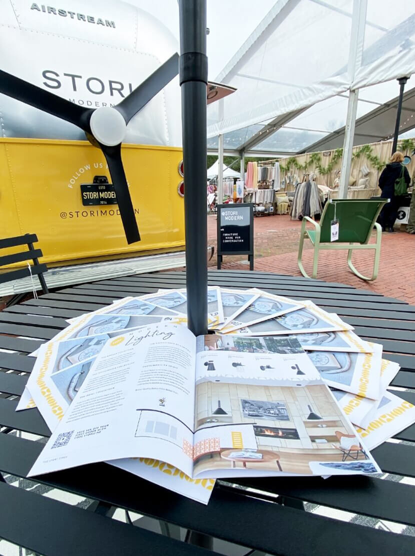Brochures on a table with the Stori Modern Airstream in the background
