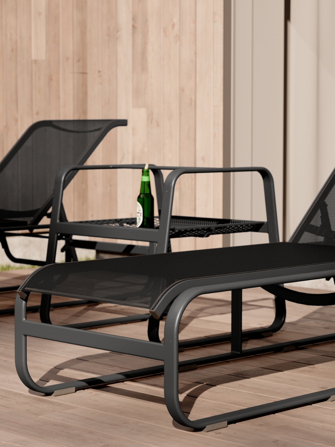 Part of the Stori Modern Sequel collection, two black mesh lounge chairs and a side table with a green beer bottle sit on a wooden deck. The classic sling chair design is set against light wood paneling and a partially visible wall in the background.